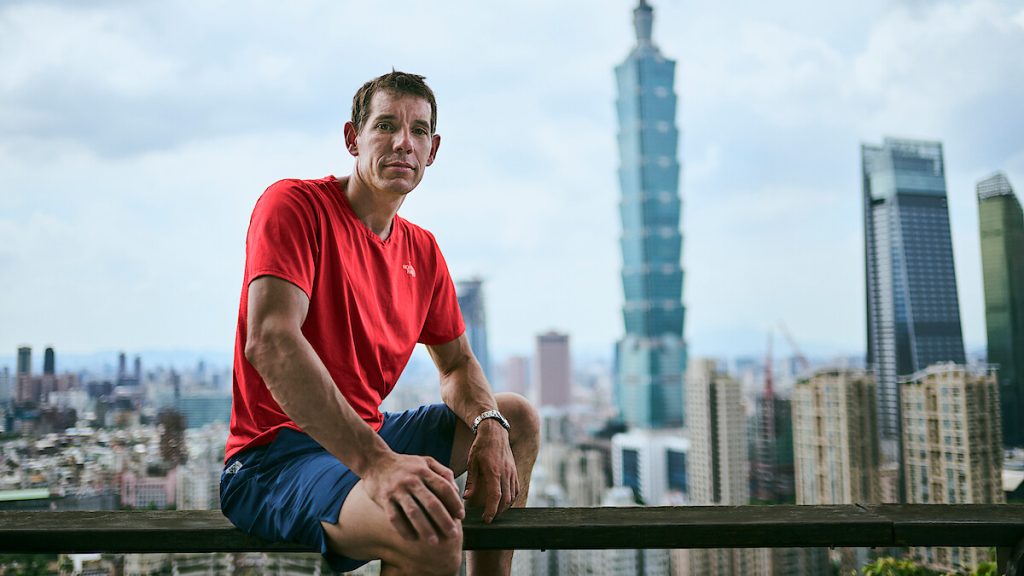 Alex Honnold posando com o Taipei 101 ao fundo, em divulgação do Skyscraper Live.